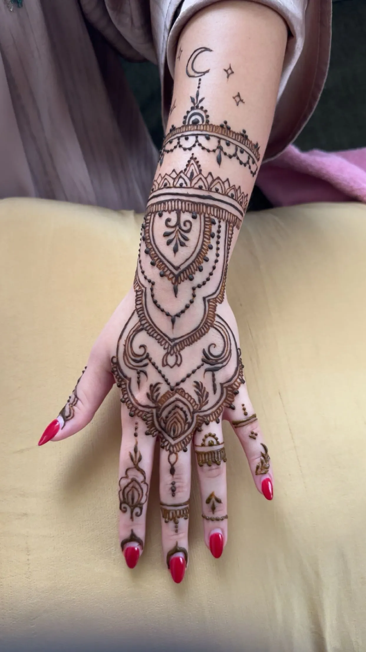 Arabic bridal henna with crescent moon and chandelier motifs on a hand in Dubai