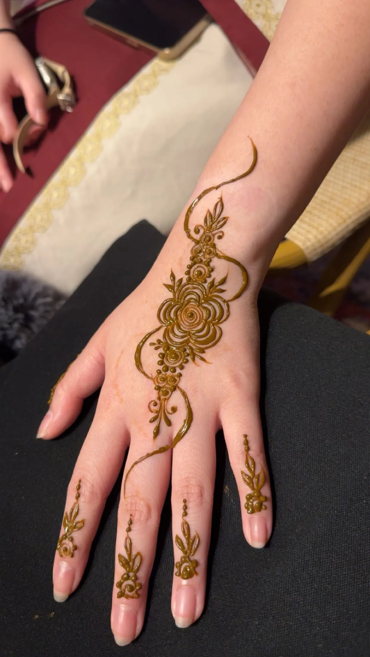 Rose mandala henna on the back of the hand with finger details